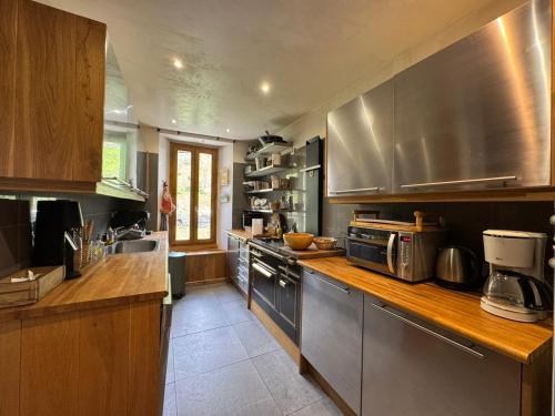 une cuisine avec des appareils en acier inoxydable et un comptoir en bois dans l'établissement LE FRANIER Splendide Chalet en Montagne - 12pers, à Sainte-Foy-Tarentaise