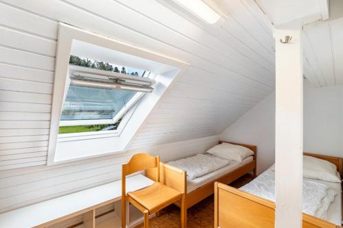 a small attic bedroom with two beds and a window at Naturerlebnishaus Gaistal in Bad Herrenalb
