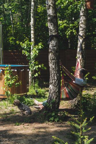 a woman sitting in a hammock in a tree at Domek nad jeziorem Strykowskim in Sapowice