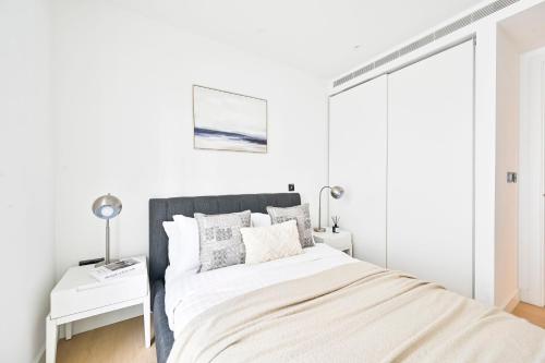 a white bedroom with a bed and a white table at Luxury 2BR Apartment - West London, Steps to Tube & Westfield Mall in London