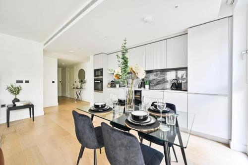 a dining room with a glass table and chairs at Luxury 2BR Apartment - West London, Steps to Tube & Westfield Mall in London