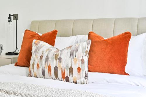 a bed with orange and white pillows on it at Luxury 2BR Apartment - West London, Steps to Tube & Westfield Mall in London