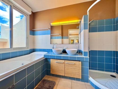 - une salle de bains bleue et blanche avec deux lavabos et une baignoire dans l'établissement La terrasse d'Eden, calme et relaxant, au Cap d'Agde