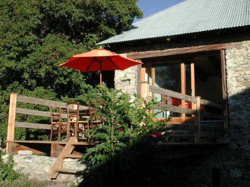 a table with an umbrella next to a house at Le Gite de la Passerelle à Crévoux in Crévoux