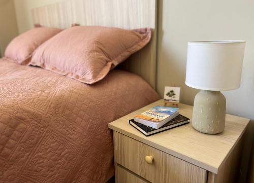 a bed with a table with a lamp and a book at Eniseli in Chakvi