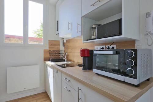 une cuisine avec un comptoir avec un micro-ondes et une cuisinière dans l'établissement Le Cocon de Lobau - Calme et Tout confort - près CHU, à Nancy