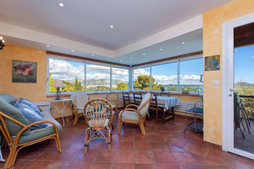 une salle à manger avec une table, des chaises et des fenêtres dans l'établissement Vue mer, à 400 m de la plage et du port, clim, Wifi, à Saint-Mandrier-sur-Mer