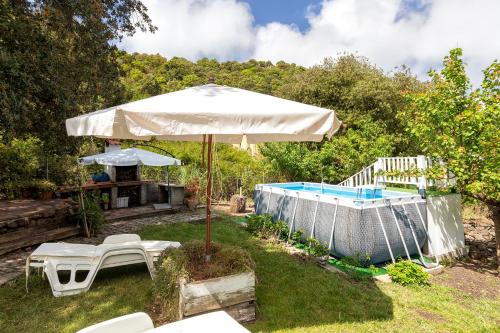 a patio with an umbrella and a pool at La casa nel bosco in Alghero