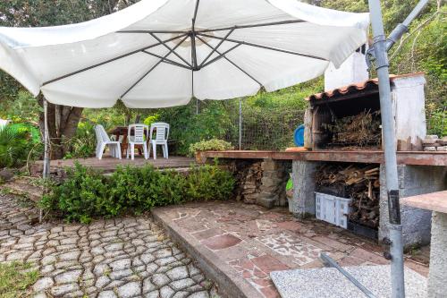 a patio with an umbrella and a table and chairs at La casa nel bosco in Alghero