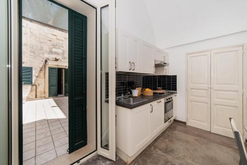 a kitchen with white cabinets and a sliding glass door at CASA PAPADIA in Uggiano la Chiesa