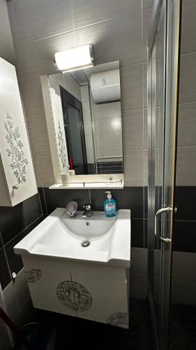 a bathroom with a white sink and a mirror at Двустаен апартамент in Ahtopol