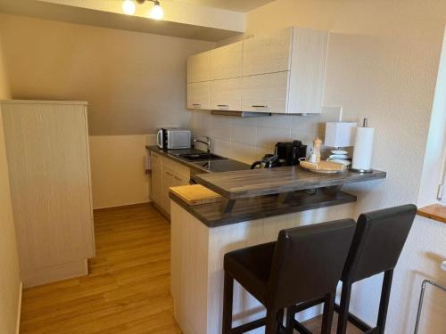 a small kitchen with a counter and chairs in it at Charmante Ferienwohnung in Neukloster mit Terrasse in Neukloster