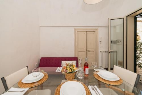 a dining room with a glass table and a red couch at CASA PAPADIA in Uggiano la Chiesa