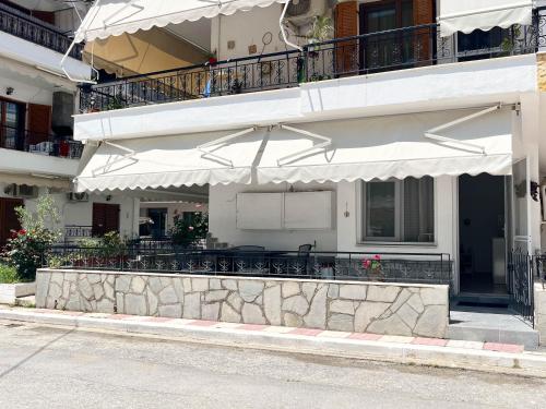 a building with a patio with tables and chairs at Veranda Apartment Paralia Ofriniou in Ofrínion