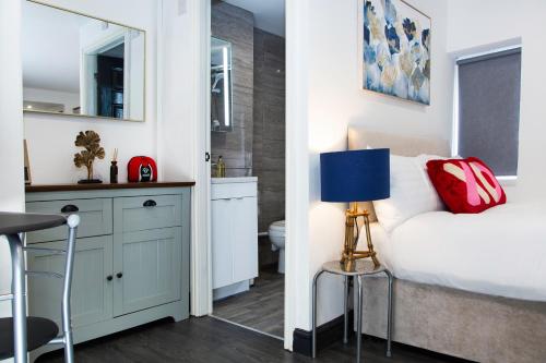 a bedroom with a bed and a desk with a blue lamp at Snuggle Cove Apartments- Walton Road in Liverpool