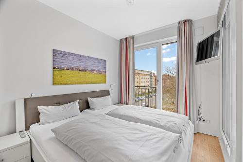 ein weißes Schlafzimmer mit einem großen Bett und einem Fenster in der Unterkunft DünenResort Binz DünenResort Binz 135 in Binz