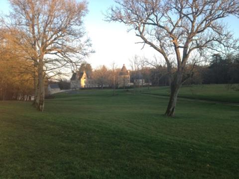 un grand champ avec des arbres et une maison en arrière-plan dans l'établissement les portes de Chenonceaux, à La Celle-sous-Gouzon
