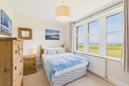 a bedroom with a bed and two windows at Host & Stay - Chirnells in Bamburgh