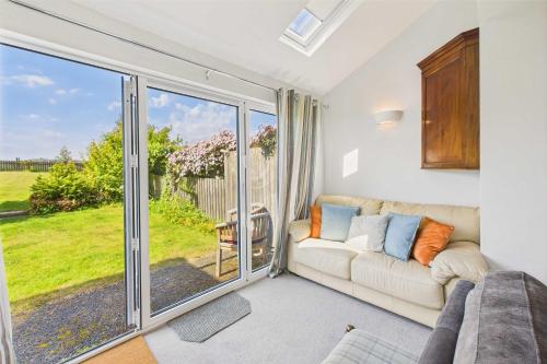 - un salon avec un canapé et une grande porte coulissante en verre dans l'établissement Host & Stay - Chirnells, à Bamburgh
