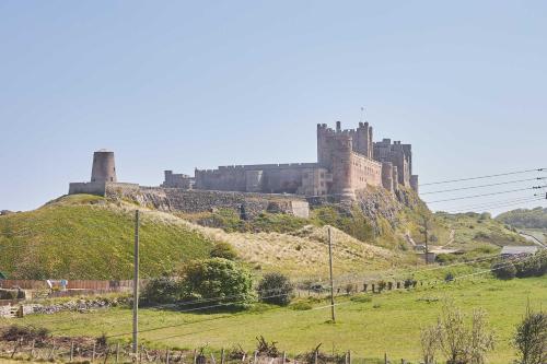 a castle sitting on top of a hill at Host & Stay - Chirnells in Bamburgh