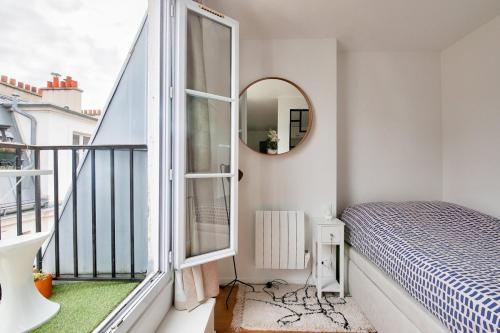 Cette chambre dispose d'un balcon avec un lit et un miroir. dans l'établissement Cosy appart cœur de Paris 2 pers, à Paris