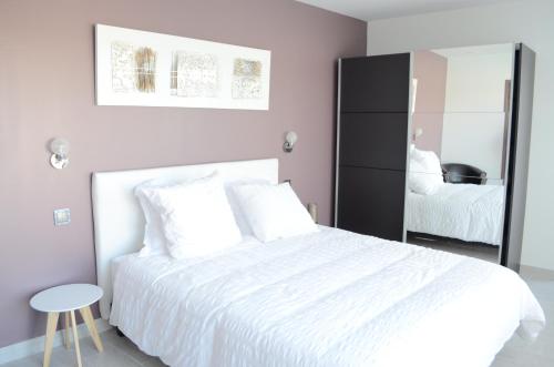 a bedroom with a white bed and a mirror at Chez Jojo & Cassi in Vert-Saint-Denis