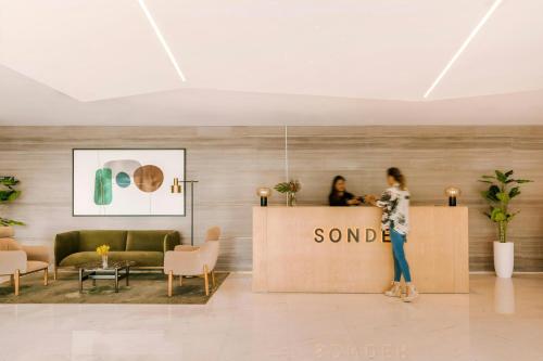 a woman standing behind a sign in a lobby at Sonder by Marriott Bonvoy Downtown Towers Apartments in Dubai