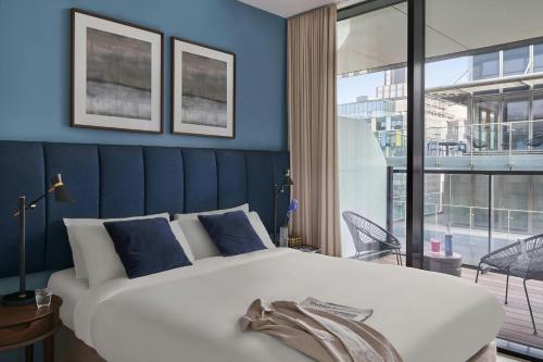 a bedroom with a large white bed with blue walls at Sonder by Marriott Bonvoy Britain Quay Apartments Grand Canal Square in Dublin