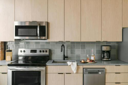 a kitchen with stainless steel appliances and wooden cabinets at Sonder by Marriott Bonvoy The Burnham Apartments Loop in Chicago