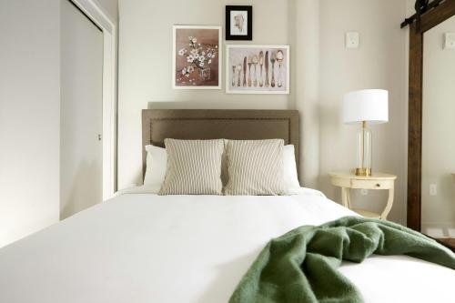 a bedroom with a white bed with a green blanket on it at Sonder by Marriott Bonvoy The Broughton Apartments Historic District in Savannah