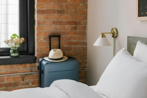 a hat sitting on top of a suitcase next to a bed at Sonder by Marriott Bonvoy The Burnham Apartments Loop in Chicago