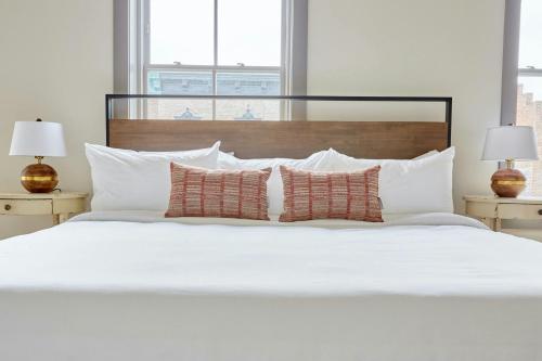 a white bed with white pillows and two lamps at Sonder by Marriott Bonvoy The Broughton Apartments Historic District in Savannah