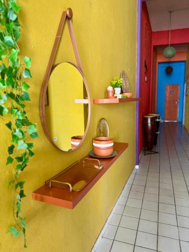 a bathroom with a mirror on a yellow wall at Pousada Cores do Pelô in Salvador