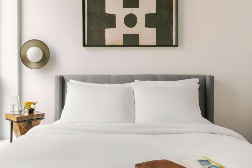 a bed with white pillows and a picture on the wall at Sonder by Marriott Bonvoy The Opal Apartments River North in Chicago