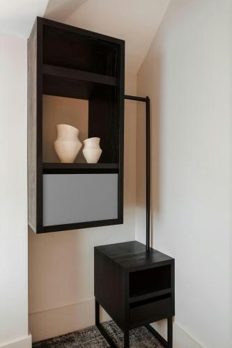 a black shelf with two white vases and a table at The Earl Hotel Leeson Street, Sonder by Marriott Bonvoy in Dublin
