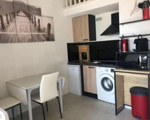 une petite cuisine avec une table et un lave-linge. dans l'établissement Palm Beach, au Cap d'Agde