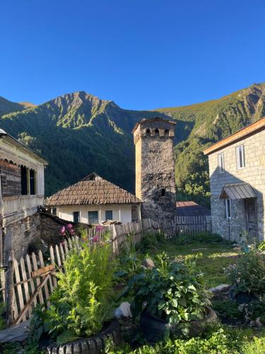 a garden in front of a house with mountains in the background at Bata GuesThouse in Adishi