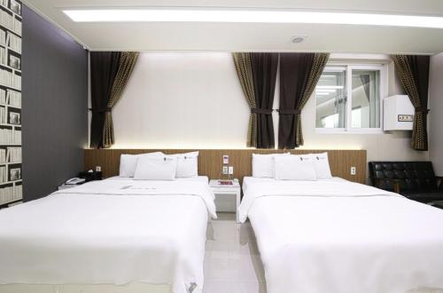 two beds in a hotel room with white sheets at Gwangju Hanam 1st Hotel in Gwangju