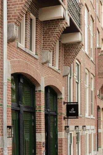 Un edificio de ladrillo con puertas verdes y un balcón. en Middelland Hotel, Sonder by Marriott Bonvoy, en Róterdam