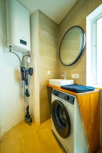 une machine à laver dans une salle de bain avec un lavabo dans l'établissement Les suites du castillet, à Perpignan