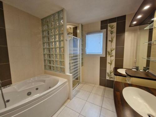 une grande salle de bain avec une baignoire et un lavabo dans l'établissement Maison piscine chauffée joli jardin paysagé, à Saint-Jean-de-Monts