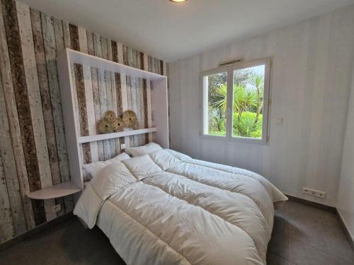 une chambre avec un grand lit et une fenêtre dans l'établissement Maison piscine chauffée joli jardin paysagé, à Saint-Jean-de-Monts