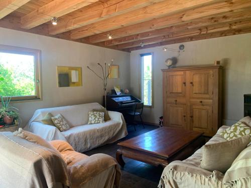 un salon avec deux canapés et un piano dans l'établissement Jolie maison en bois avec piscine, à Saint-Césaire-de-Gauzignan