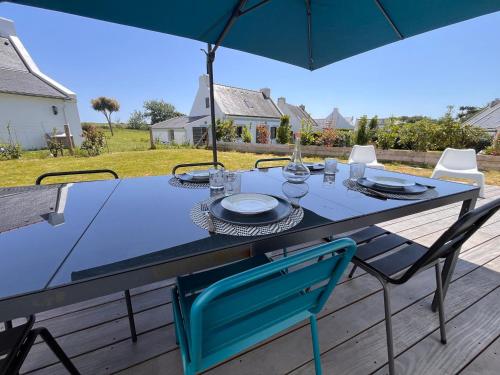 une table bleue avec des chaises et un parasol sur une terrasse dans l'établissement Maison indépendante à Pouldon, proche plage, 4 chambres, jardin - FR-1-418-262, à Locmaria