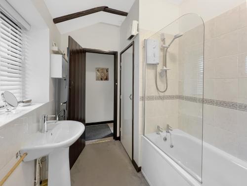 a white bathroom with a sink and a shower at Dairy Cottage Dulverton in Dulverton