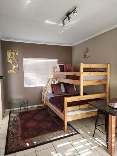 a bedroom with two bunk beds and a table at Rudman Townhouses - OR Tambo Airport in Boksburg
