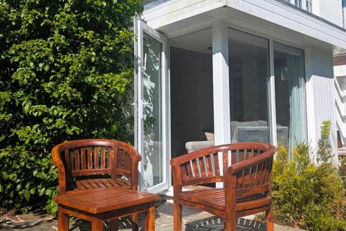 two wooden benches sitting on the porch of a house at Mill End Hotel in Chagford