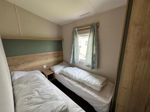 a small bedroom with two beds and a window at Dainville Caravan Park in Skegness