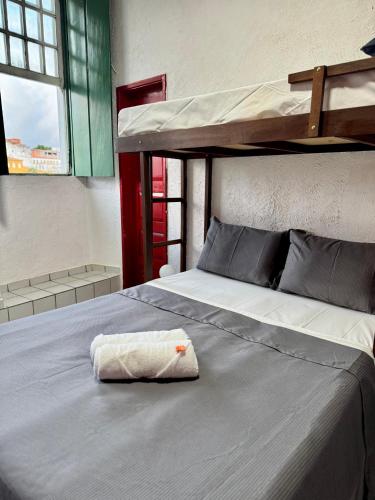 a bed with a towel laying on top of it at Pousada Cores do Pelô in Salvador