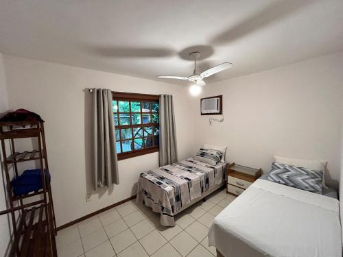 a bedroom with two beds and a window at Casa Quinta do Atlântico - Aconchego da Paz 150m da praia in Búzios